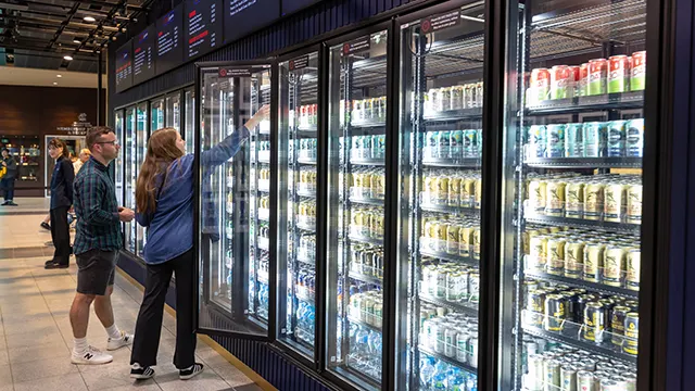 Patrons selecting a drink from multiple large fridges