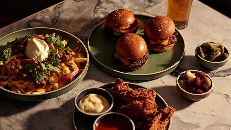 Burger sliders and meals plated with beer, olives and pickles