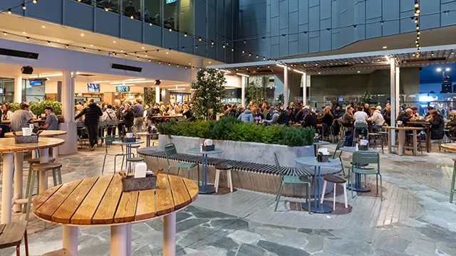 Patrons seated outdoors with cafe tables and hanging lights.