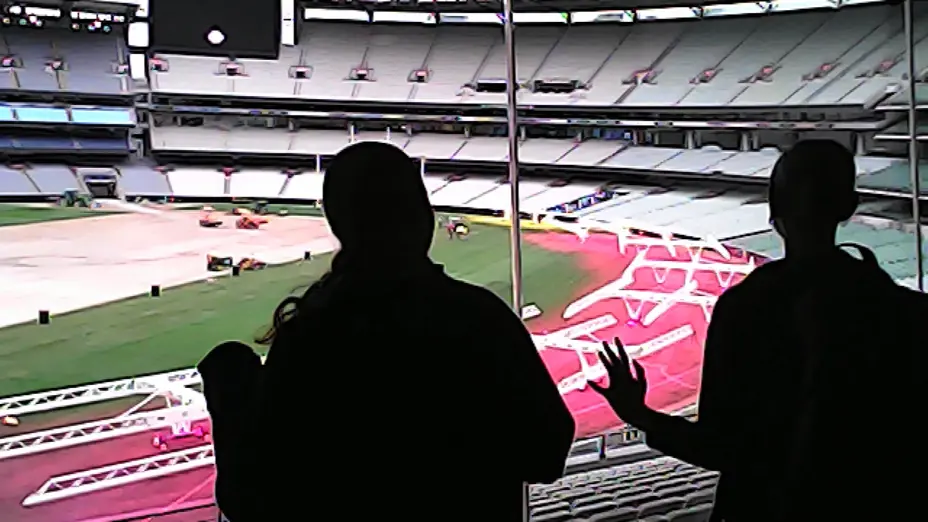 Silhouette of students looking at MCG turf through glass pane