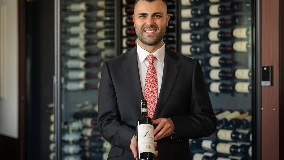 A man holding a bottle of wine in the Committee Room by Grossi