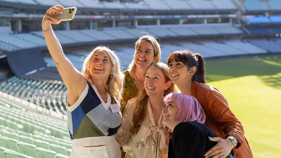 Five women taking a selfie together in the stands at the MCG