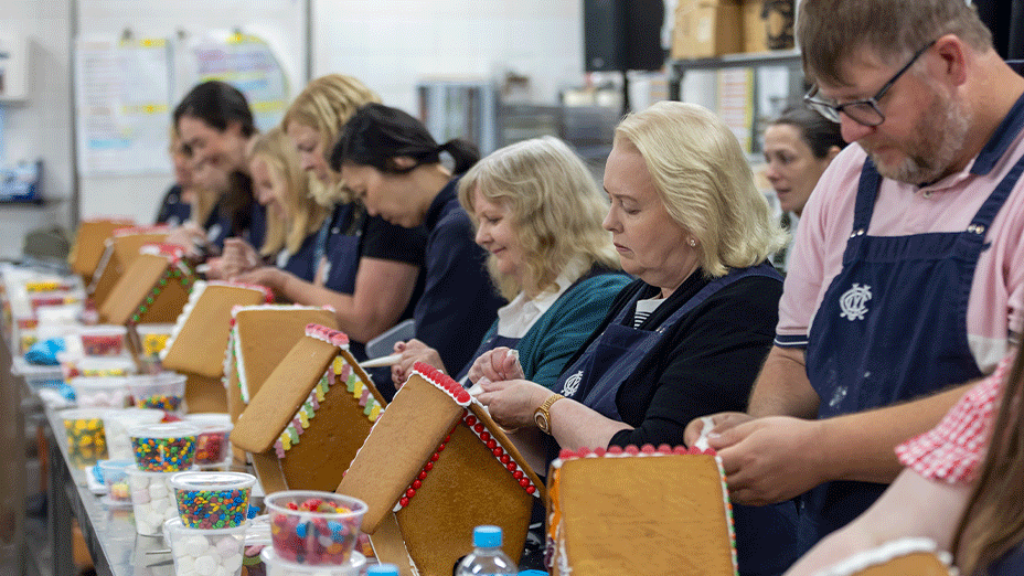 Row of participants decorating gingerbread houses