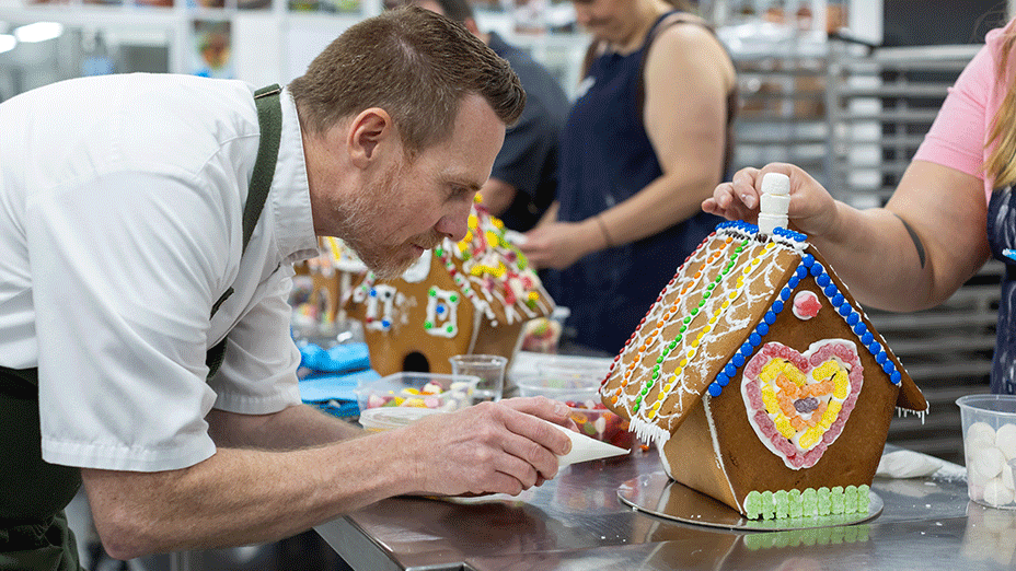 Chef places final decorations on gingerbread house